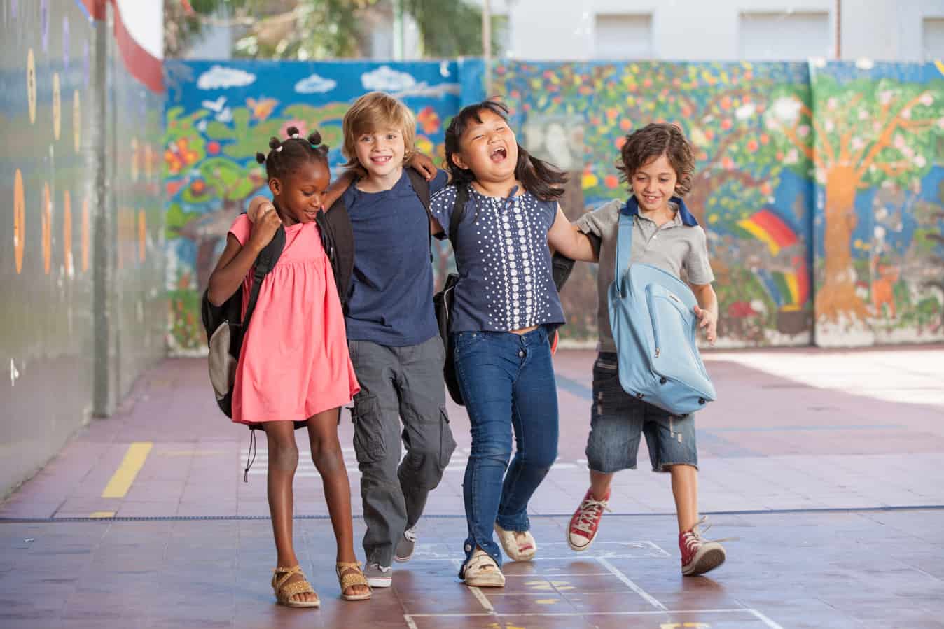 A group of four schoolkids laughs while walking around a school. Boulder Valley Schools have an excellent reputation in Colorado.